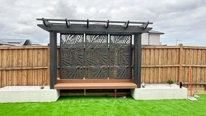 Backyard with a pergola, decorative screen, bench and lawn